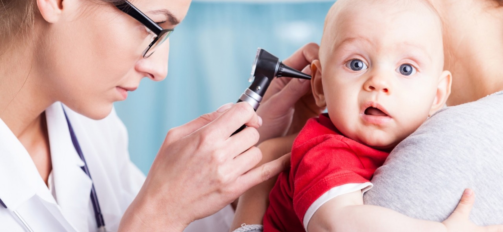 Doctor examining baby boy with otoscope