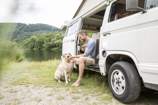 Mann mit Hund ist in seinem Van unterwegs und nimmt sich eine Auszeit