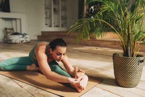 Frau beim Stretching auf einer Yogamatte im Wohnzimmer