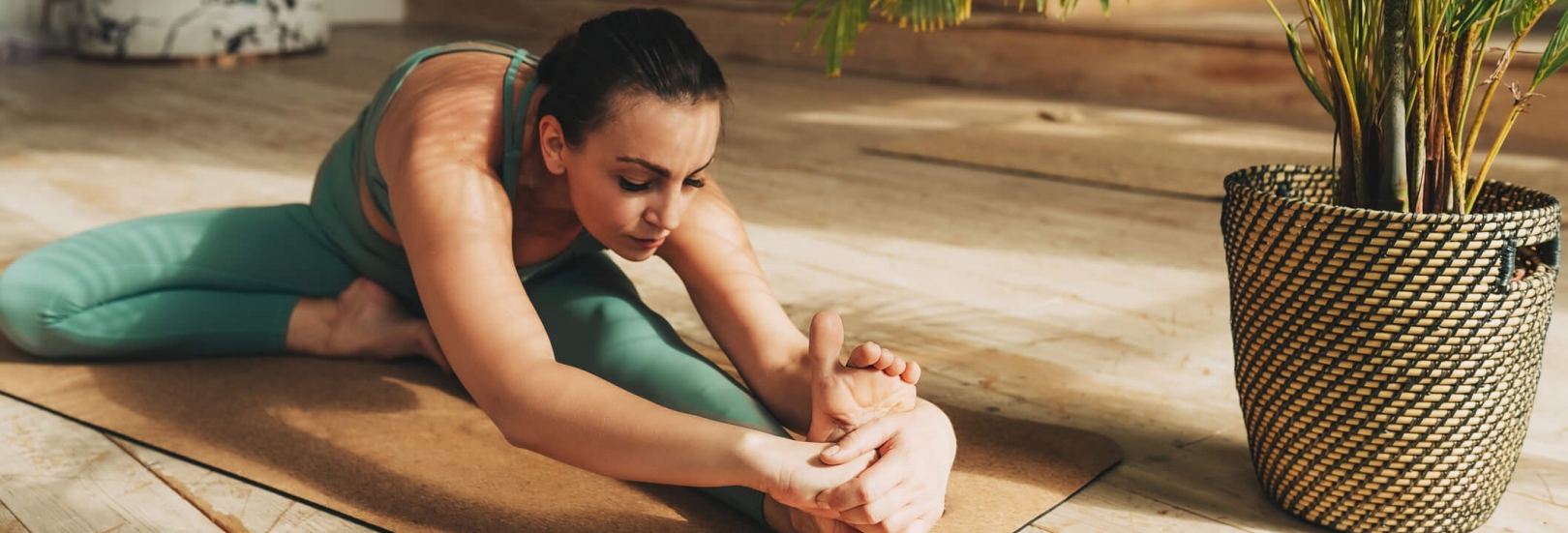 Frau beim Stretching auf einer Yogamatte im Wohnzimmer