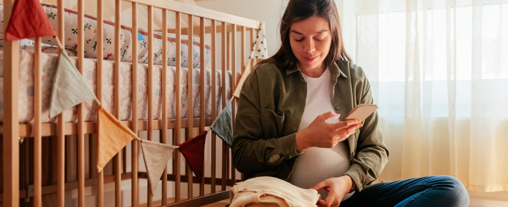 Frau sitzt schwanger in einem Kinderzimmer
