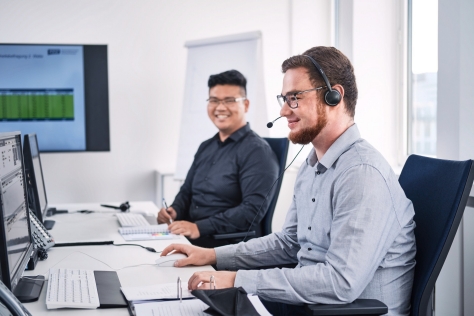 Zwei Kollegen im Büro mit Headset und Lächeln