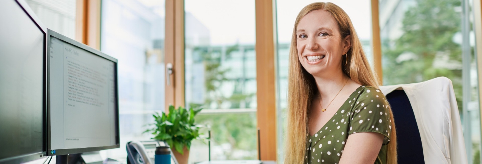 Frau am Arbeitsplatz schaut lächelnd in die Kamera