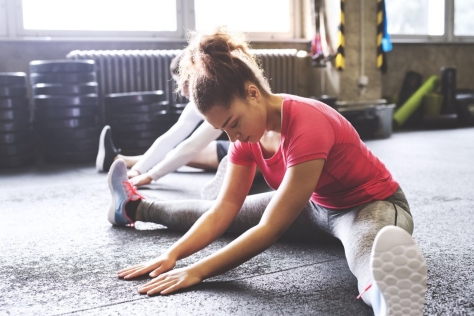 Eine Frau dehnt sich im Fitnessstudio.
