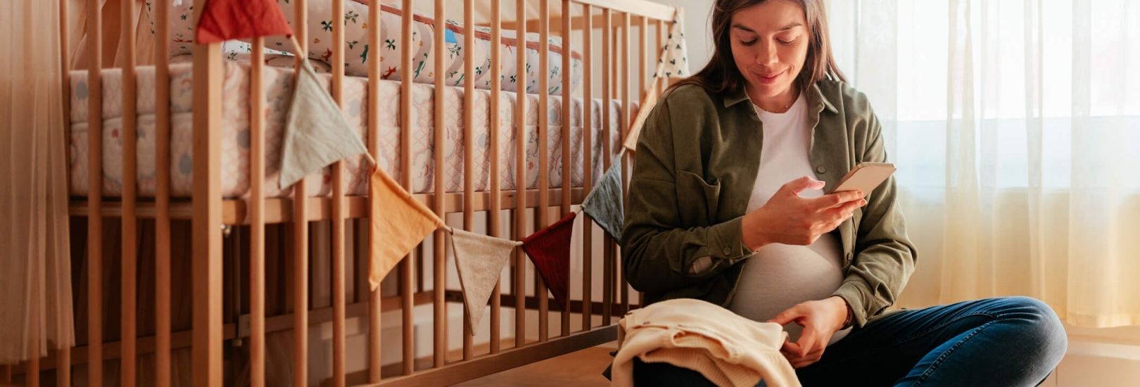 Frau sitzt schwanger in einem Kinderzimmer