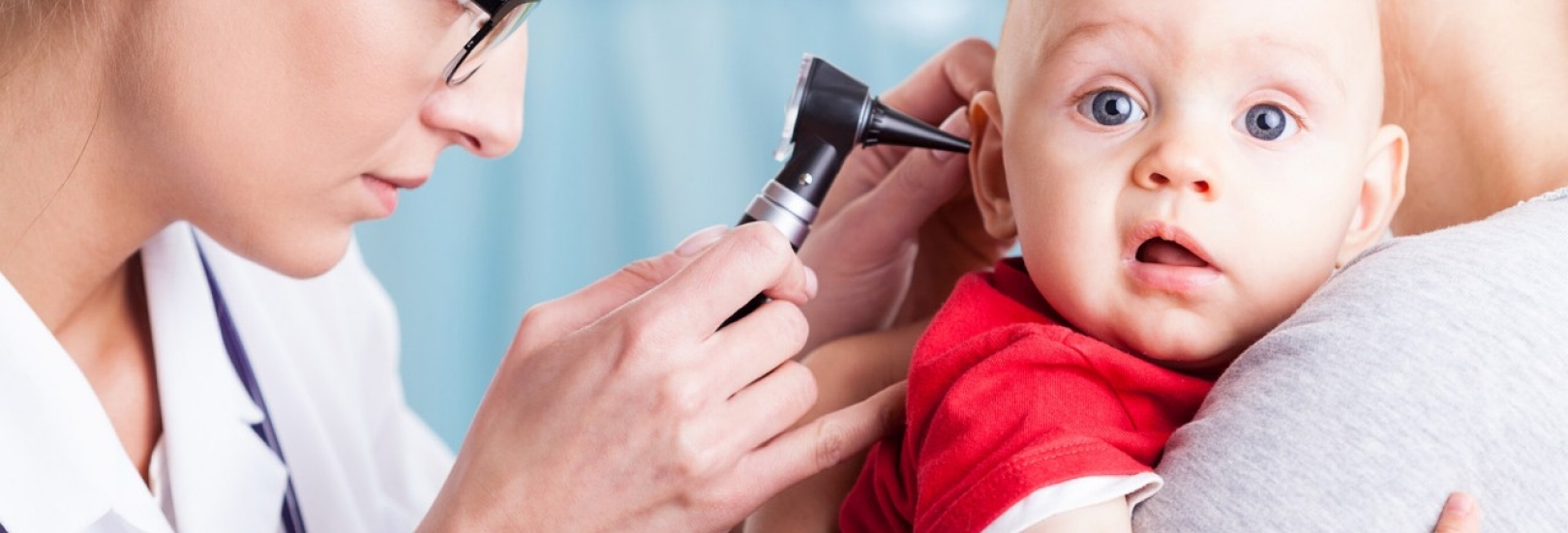 Doctor examining baby boy with otoscope
