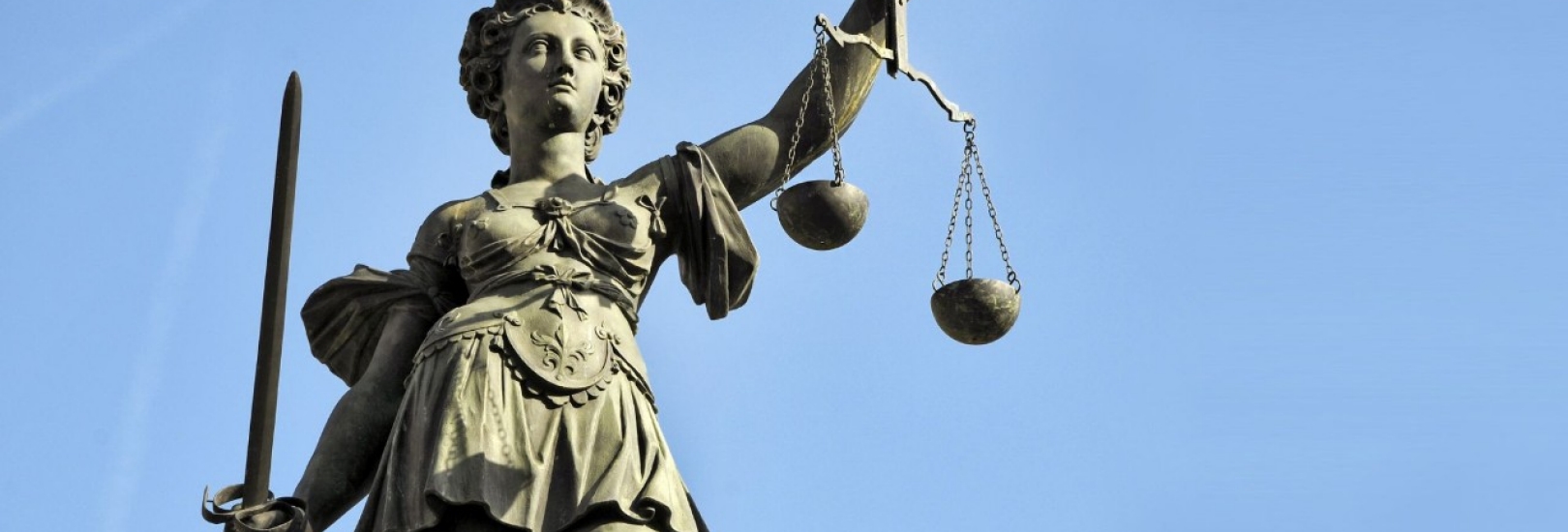 Abgebildet ist die Gerechtigkeitsgöttin Justizia als Bronze Statur. 