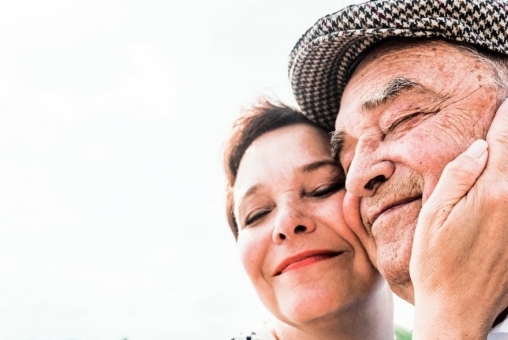 Eine Frau hält ihren Vater liebevoll im Gesicht.