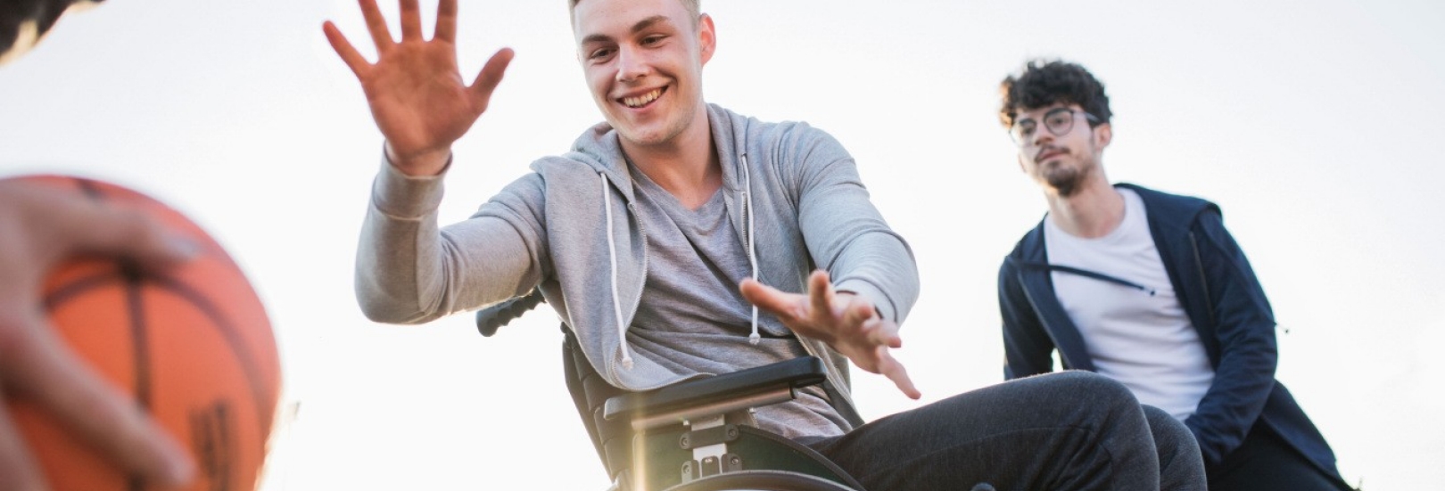 Jugendlicher im Rollstuhl spielt mit anderen Jugendlichen Basketball
