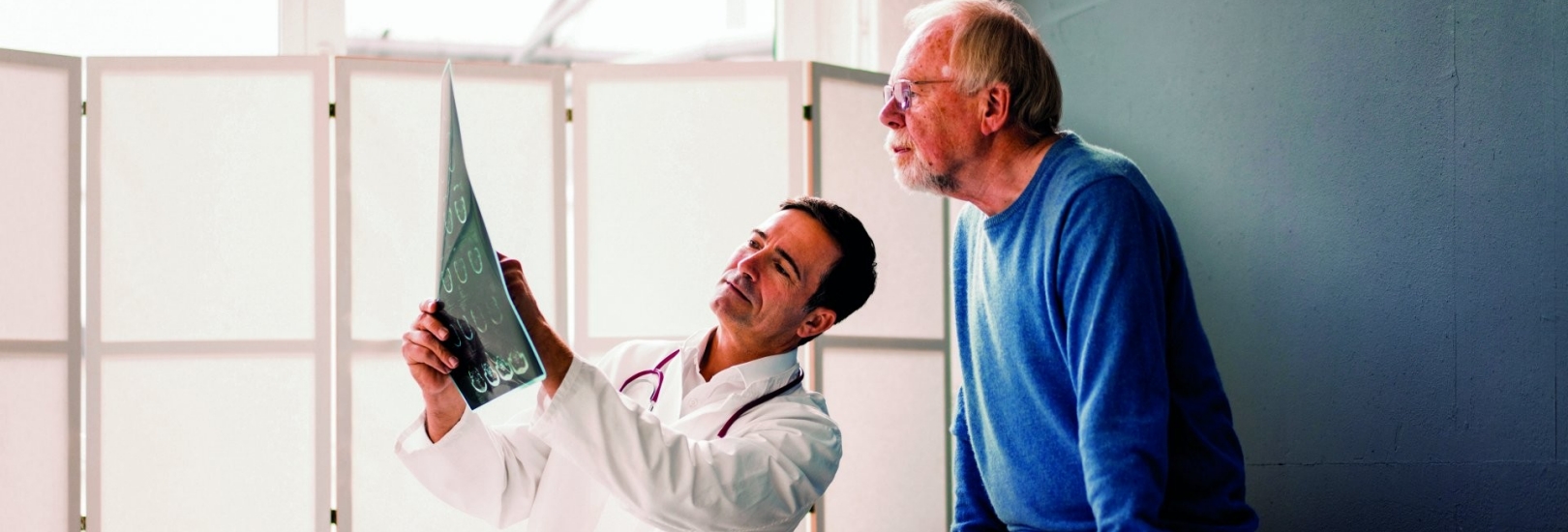 Ein junger Arzt bespricht mit einem älteren Patienten Ergebnisse.