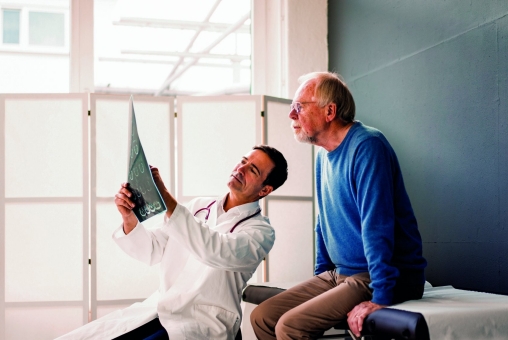 Ein junger Arzt bespricht mit einem älteren Patienten Ergebnisse.