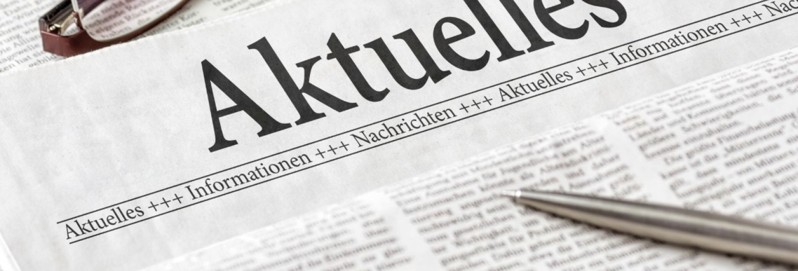 Abgebildet ist eine Zeitung mit der Überschrift Aktuelles. Zusätzlich liegen eine Brille sowie ein Kugelschreiber auf der Zeitung.