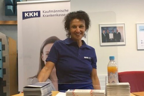 Eine Frau schaut lächelnd in die Kamera. Sie trägt ein KKH Polo Shirt.