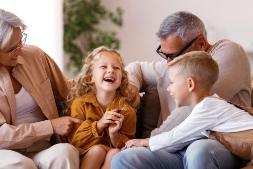 Zwei junge Kinder spielen mit ihren Großeltern auf dem Sofa.